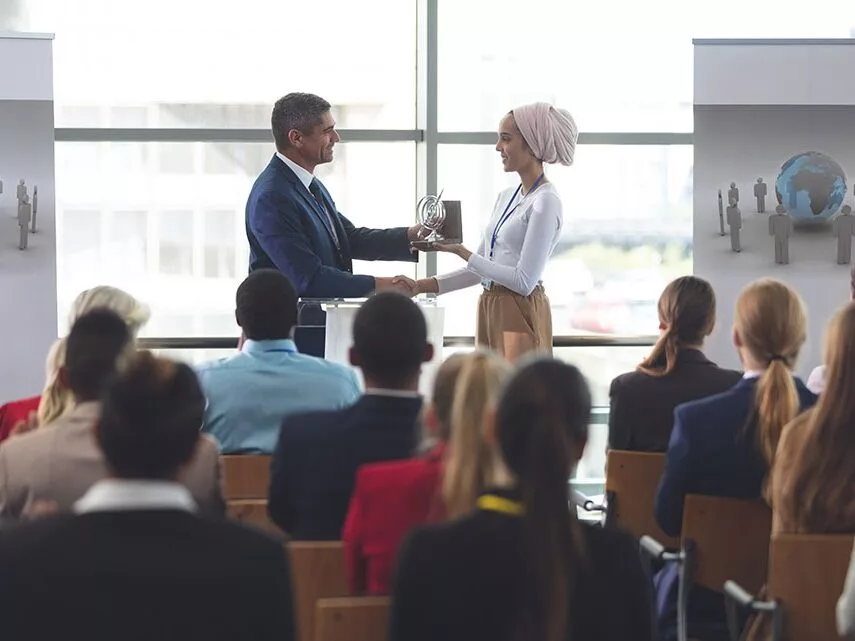 Businesswoman receiving award from businessman in a business sem
