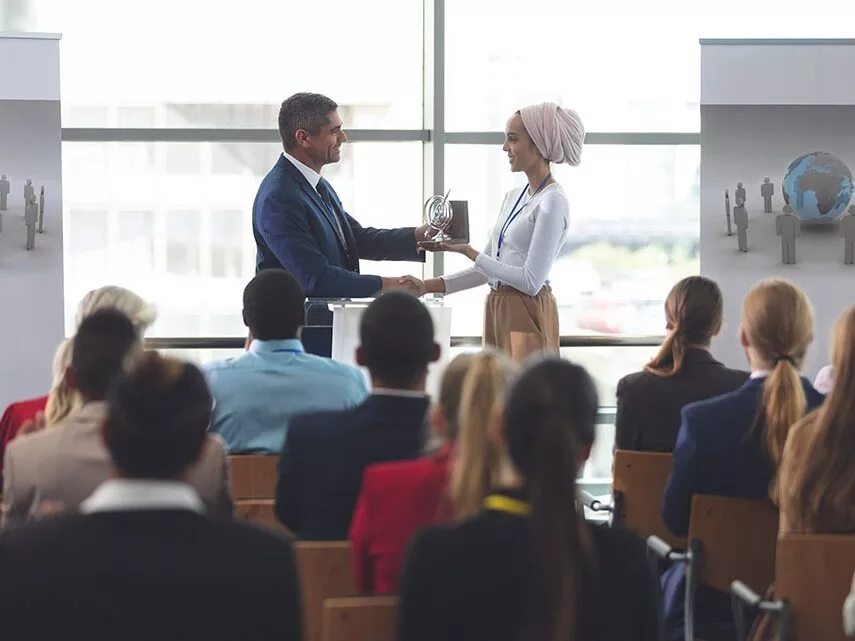 Businesswoman receiving award from businessman in a business sem